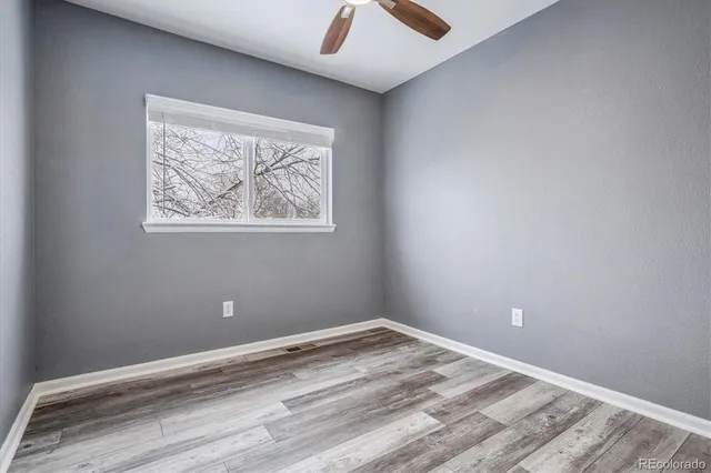 an empty room with a window and a ceiling fan