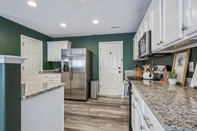 a kitchen with stainless steel appliances granite countertop a refrigerator a stove and a sink