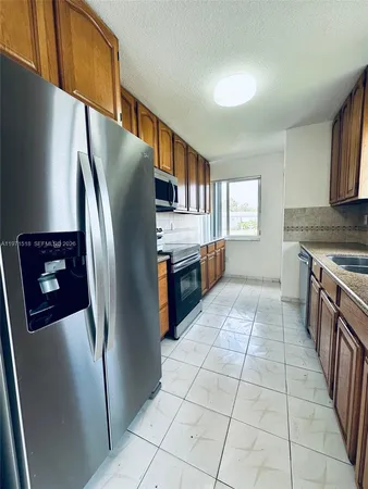 a kitchen with stainless steel appliances granite countertop a refrigerator a stove and a sink