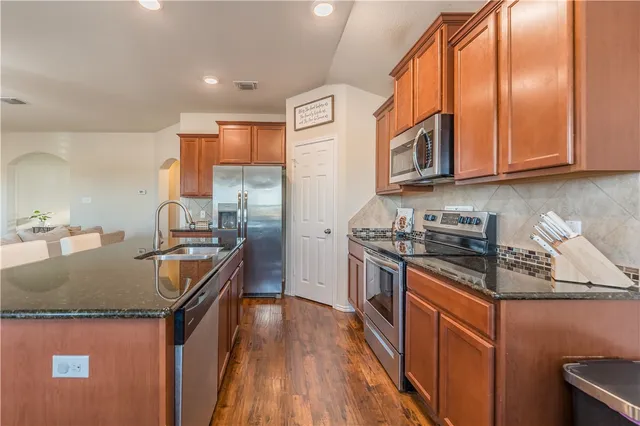 a kitchen with stainless steel appliances granite countertop a stove a sink dishwasher and cabinets with wooden floor