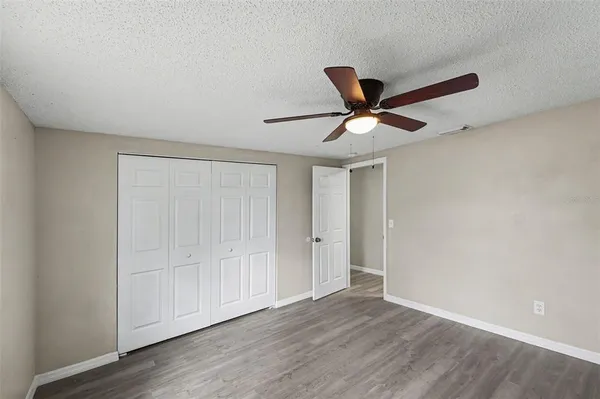 an empty room with wooden floor and ceiling fan