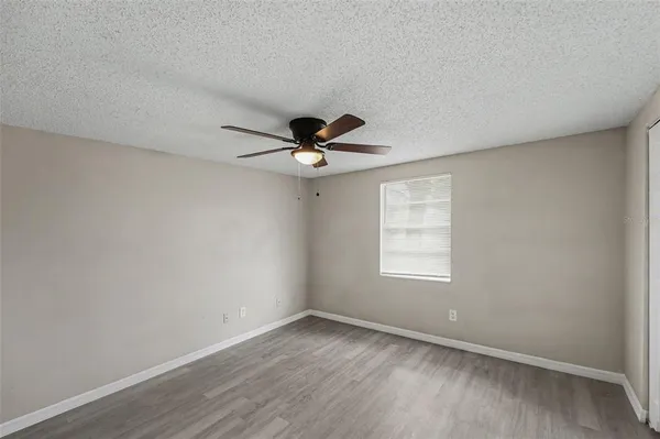 an empty room with wooden floor fan and windows