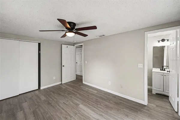 a view of an empty room with wooden floor and a ceiling fan
