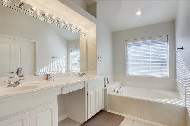 a bathroom with a tub a sink and mirror