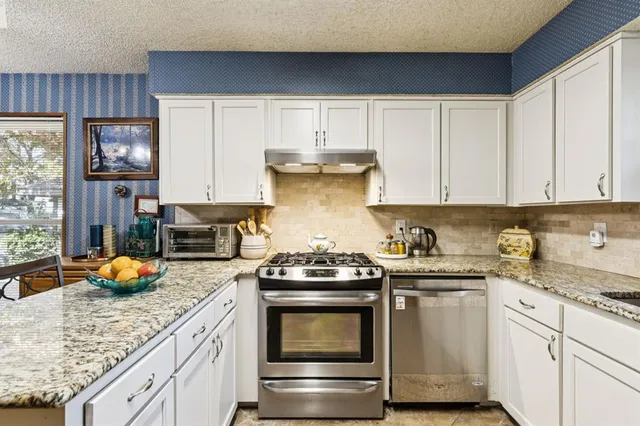 a kitchen with granite countertop white cabinets and stainless steel appliances
