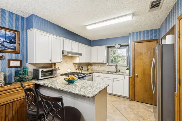 a kitchen with stainless steel appliances granite countertop a stove refrigerator sink and cabinets