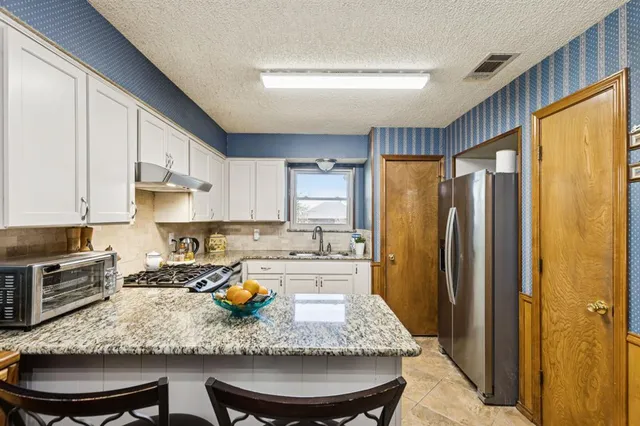 a kitchen with stainless steel appliances granite countertop a sink refrigerator stove and microwave