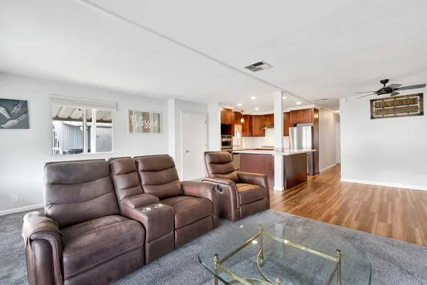 a kitchen with stainless steel appliances granite countertop a refrigerator a oven a sink and white cabinets with wooden floor