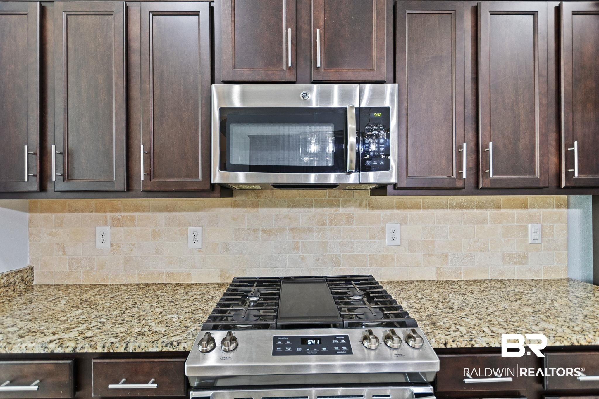 31541 Hoot Owl Road Daphne, AL 36527 - Photo 16 of 51 Kitchen with dark brown cabinetry, decorative backsplash, light stone countertops, and stainless steel appliances