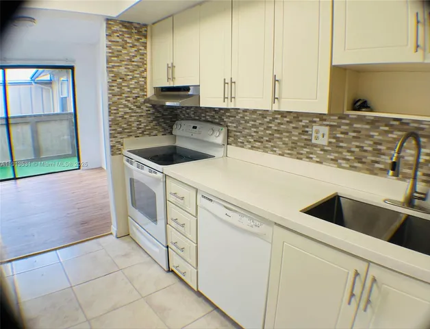 a kitchen with granite countertop white cabinets and white appliances