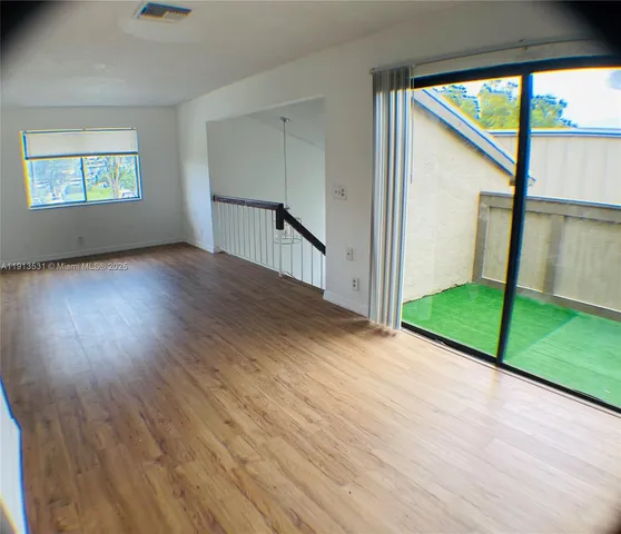 a view of an empty room with window wooden floor and front door