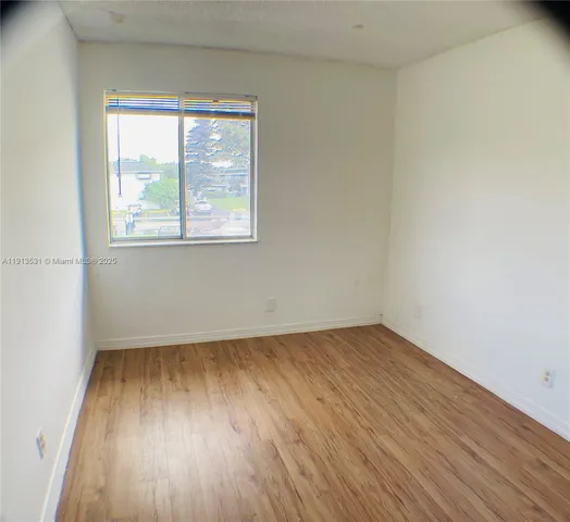 a view of an empty room with wooden floor and closet