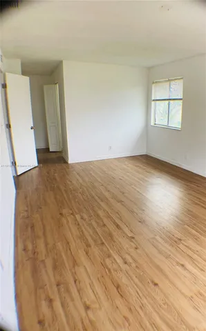 an empty room with wooden floor and window