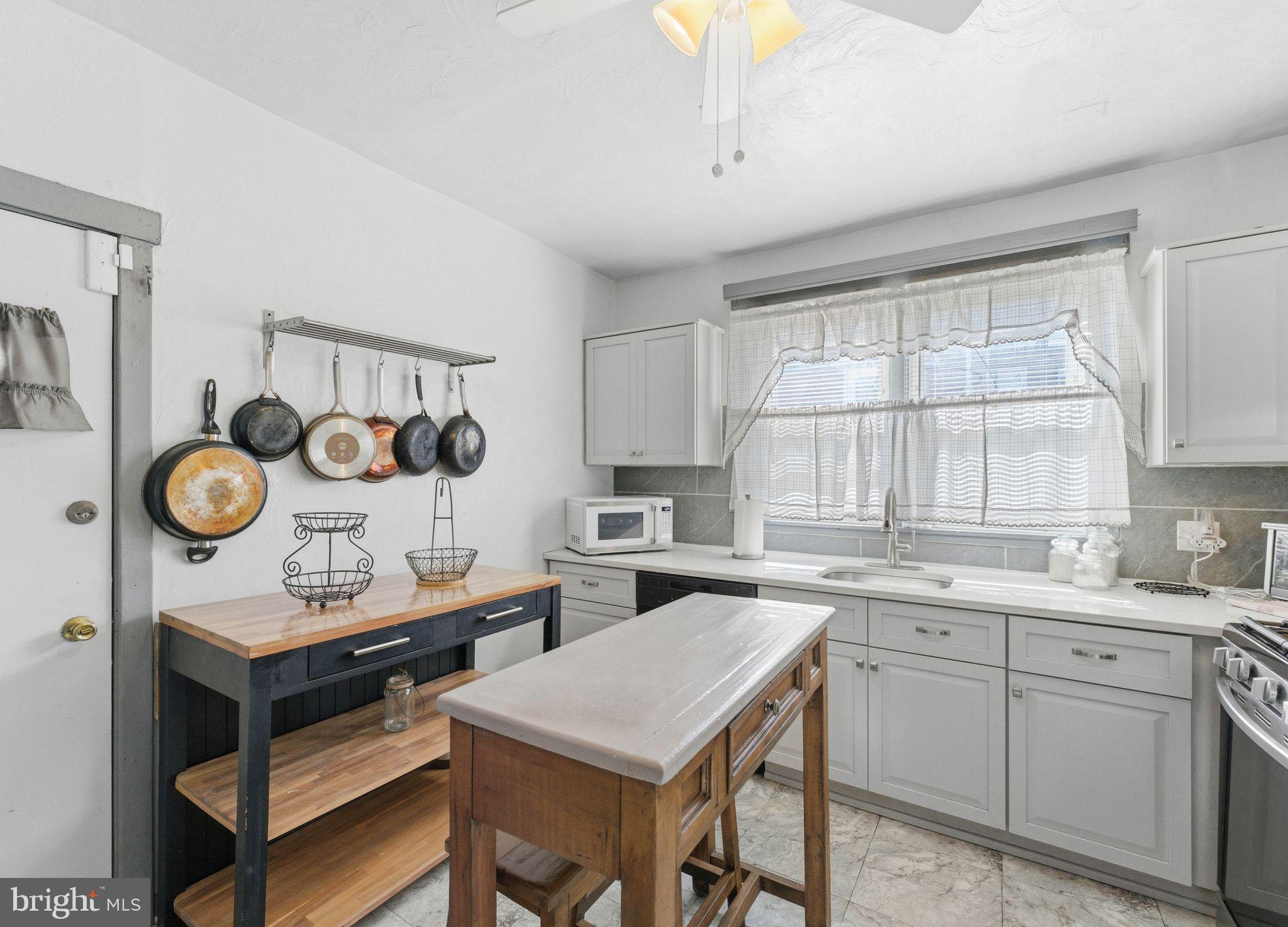 7828 Michener Avenue Philadelphia, PA 19150 - Photo 11 of 23 a kitchen with a stove a sink and a clock on the wall