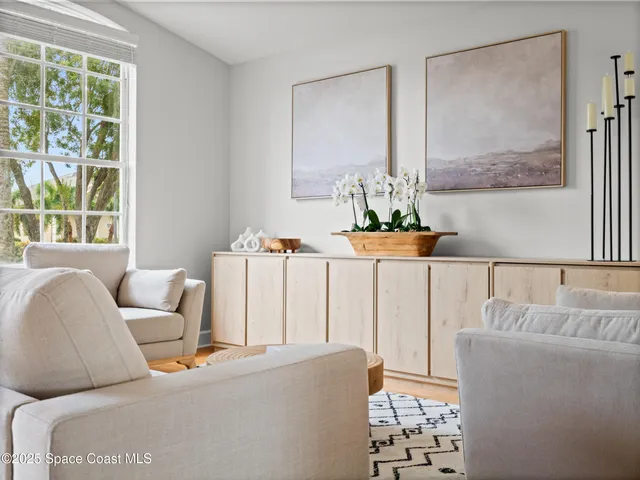 a dining room with furniture a rug a potted plant and wooden floor