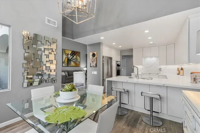 a living room with stainless steel appliances furniture a rug and a kitchen view