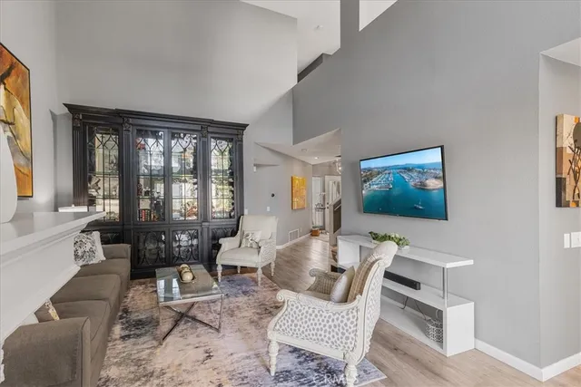 a living room with furniture two large window and a flat screen tv