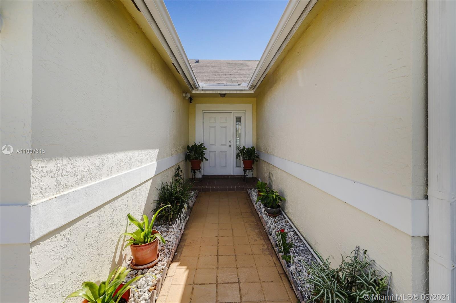5140 Northwest 5th Avenue Boca Raton, FL 33487 - Photo 4 of 44 a hallway with wooden floor and a potted plant