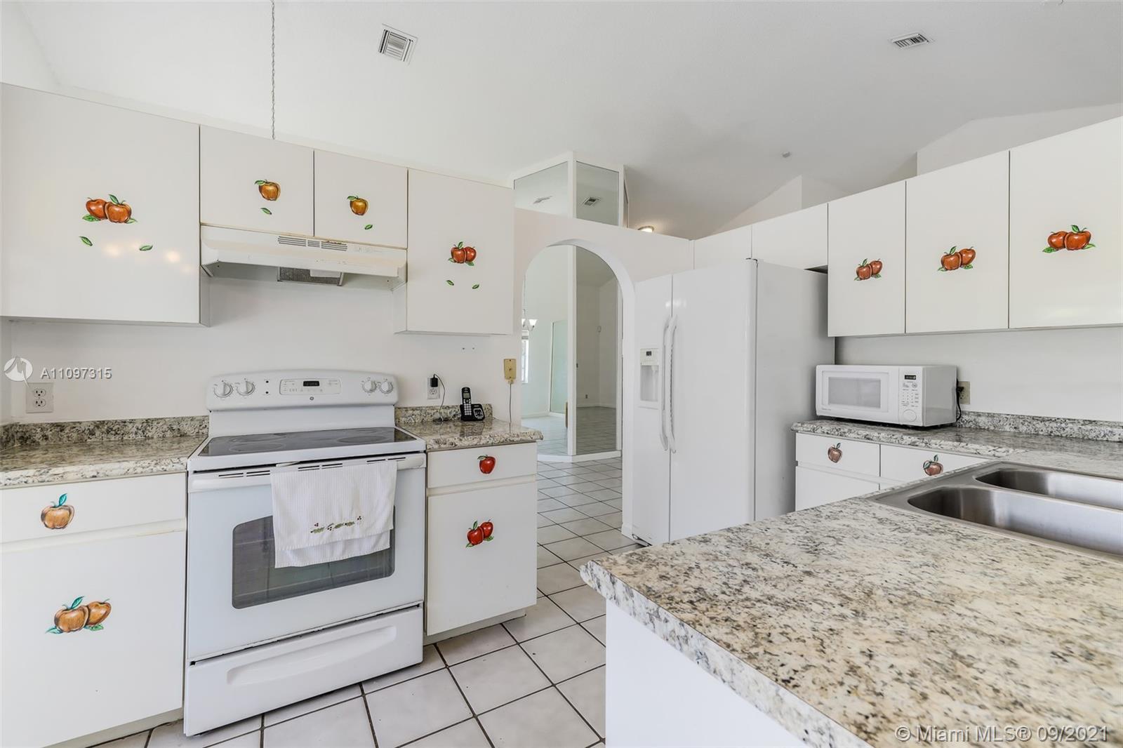 5140 Northwest 5th Avenue Boca Raton, FL 33487 - Photo 42 of 44 a kitchen with kitchen island sink stove and refrigerator