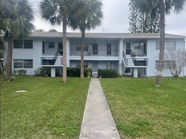 a front view of a house with a yard and palm tree