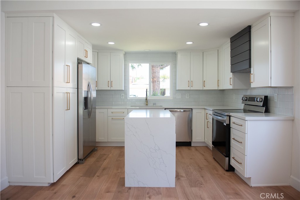 1466 East Helmick Street Carson, CA 90746 - Photo 5 of 32 a kitchen with kitchen island granite countertop a refrigerator oven a sink dishwasher and white cabinets with wooden floor