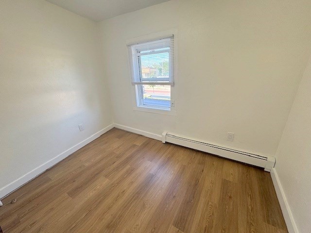 296 Broadway, Unit 2 Somerville, MA 02145 - Photo 13 of 13 an empty room with wooden floor and windows