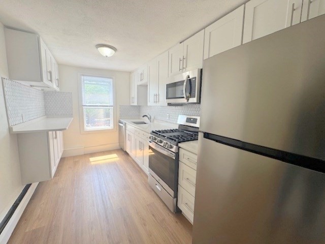 296 Broadway, Unit 2 Somerville, MA 02145 - Photo 2 of 13 a kitchen with stainless steel appliances a refrigerator sink and microwave