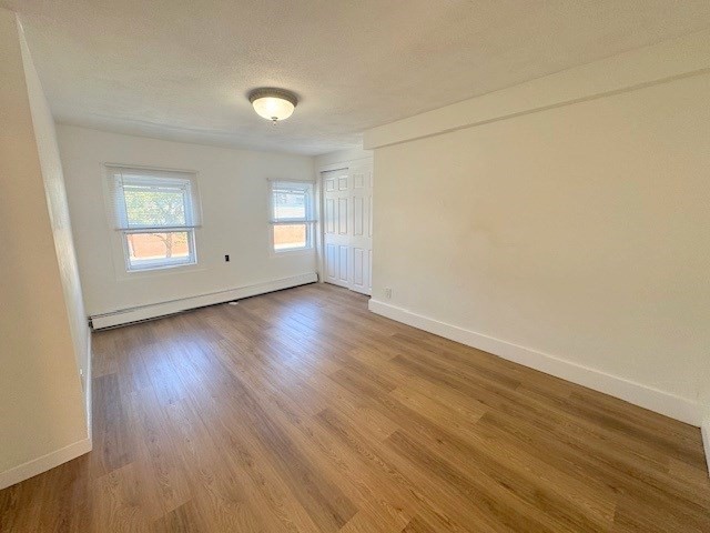 296 Broadway, Unit 2 Somerville, MA 02145 - Photo 6 of 13 an empty room with wooden floor and windows