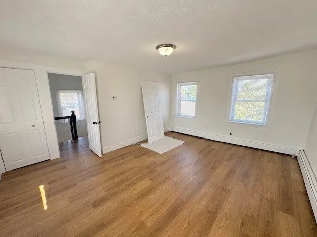 an empty room with wooden floor and windows