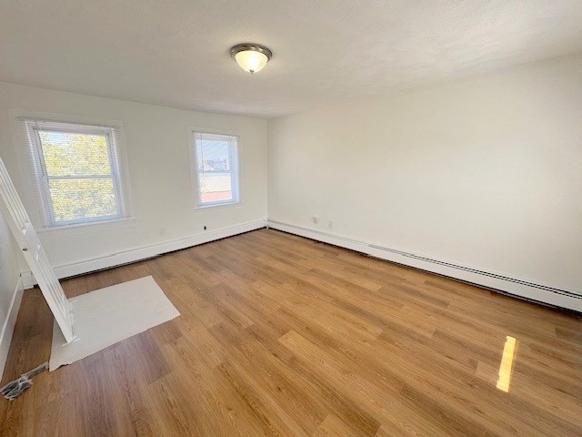 296 Broadway, Unit 2 Somerville, MA 02145 - Photo 9 of 13 an empty room with wooden floor and windows