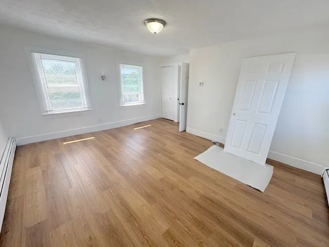 an empty room with wooden floor and windows