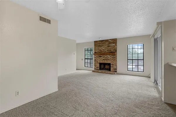 an empty room with windows and fireplace