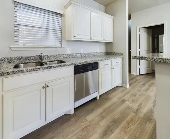 a kitchen with granite countertop a sink and cabinets
