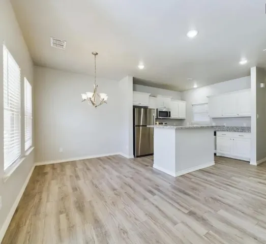 a view of a room with wooden floor fridge and a window