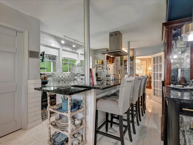a kitchen with stainless steel appliances kitchen island granite countertop a table and chairs in it