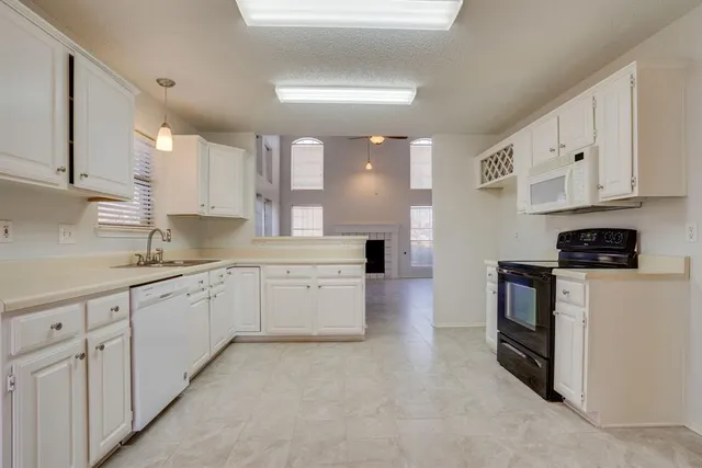 a kitchen with granite countertop white cabinets and white appliances