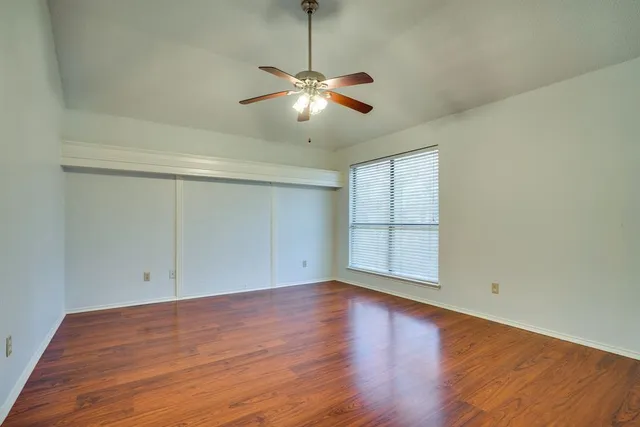 an empty room with wooden floor and a ceiling fan