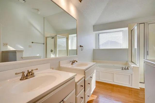 an empty room with wooden floor chandelier fan and windows