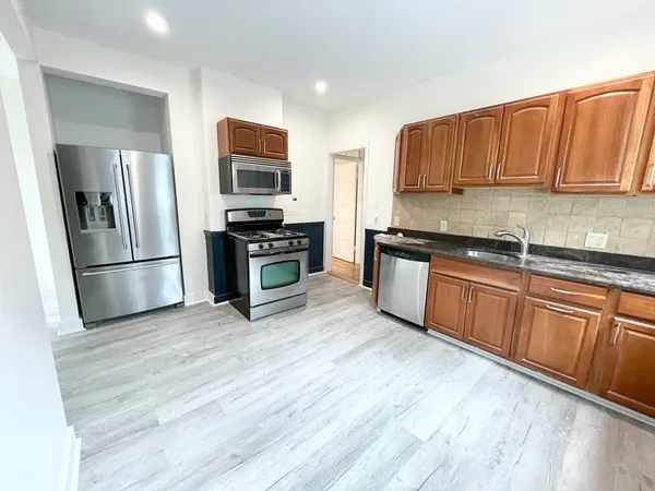 a kitchen with stainless steel appliances granite countertop a refrigerator a stove top oven a sink and dishwasher