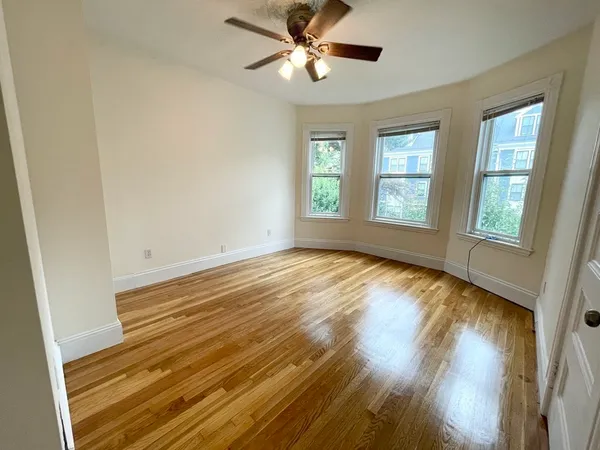 a view of empty room with wooden floor and fan