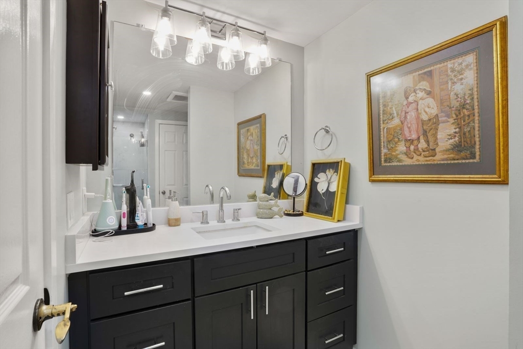 1 Commodore Court, Unit 104 Hull, MA 02045 - Photo 24 of 35 a bathroom with a double vanity sink and a mirror