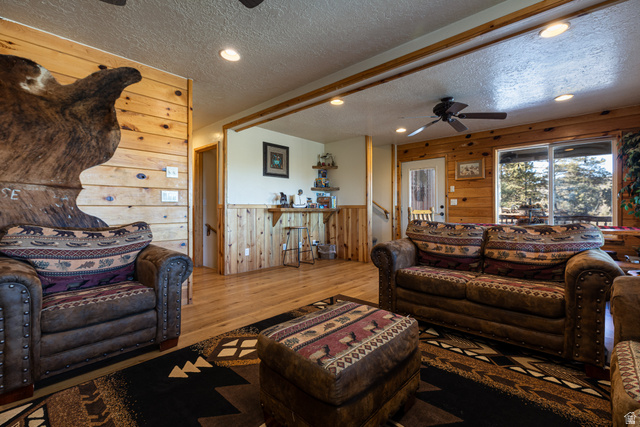 1505 West Elk Ridge Drive Alton, UT 84710 - Photo 37 of 53 Living room with wooden walls, a ceiling fan, recessed lighting, a textured ceiling, and hardwood / wood-style flooring