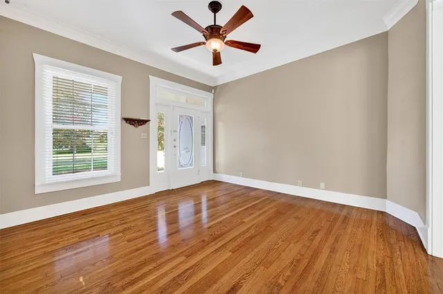 an empty room with wooden floor and windows