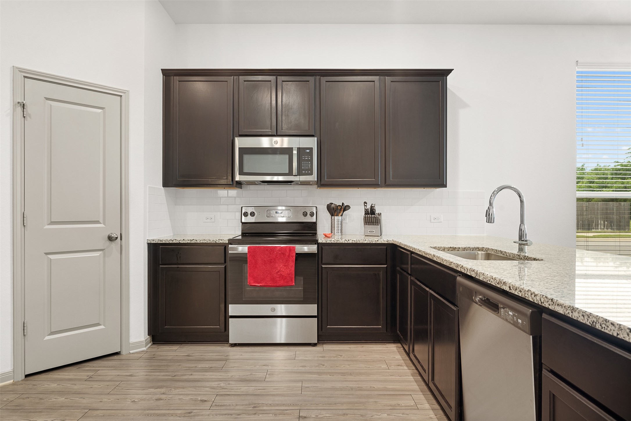 1968 Chief Street Bryan, TX 77807 - Photo 5 of 27 This modern kitchen features dark wood cabinets, stainless steel appliances, and granite countertops. It offers a bright, open feel with a large window and sleek fixtures. Perfect for cooking and entertaining.