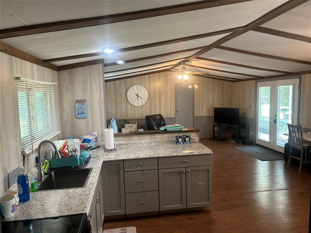 4705 Fox Hollow Road Graham, TX 76450 - Photo 28 of 28 Kitchen with gray cabinets, open floor plan, wood walls, a peninsula, and dark wood finished floors