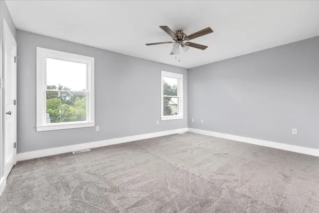 an empty room with a window and a fan