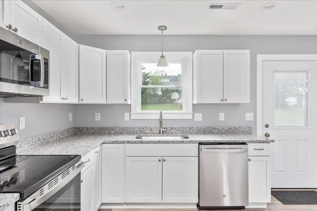 a kitchen with granite countertop a sink white cabinets and white appliances