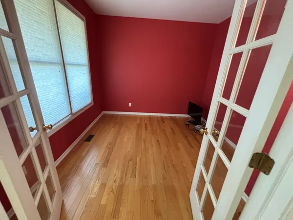 a view of an empty room with wooden floor and stairs