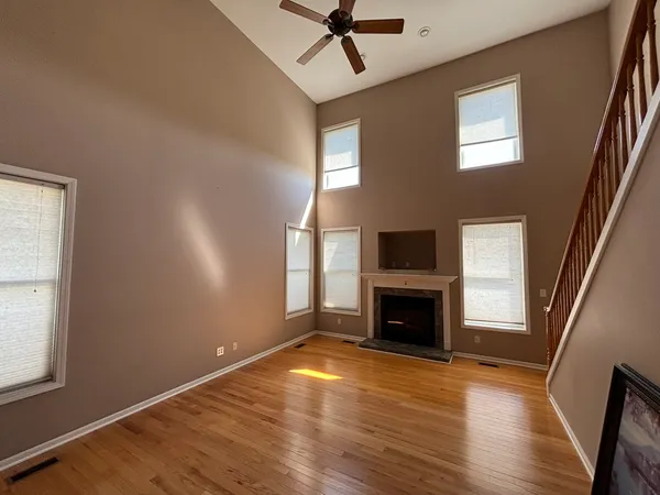 an empty room with windows fireplace and wooden floor