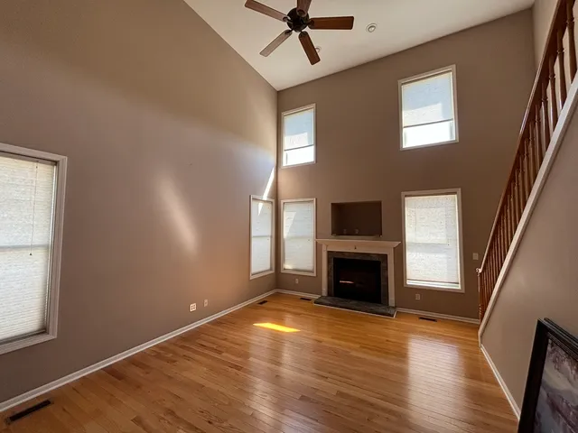 an empty room with windows fireplace and wooden floor